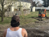 A man wearing a First Class Contracting shirt oversees construction in the backyard of a home